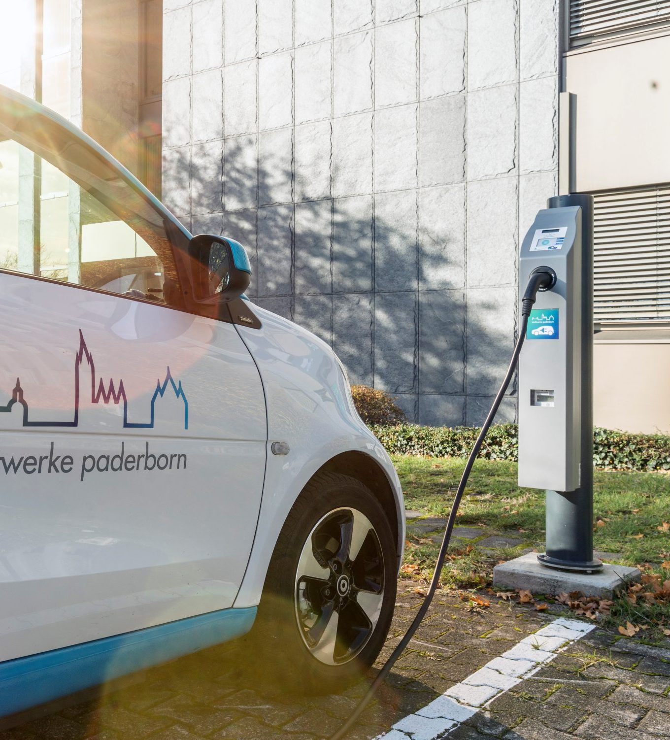 Kleines weißes Auto mit dem Stadtwerk Paderborn Logo steht an einer E-Ladestation