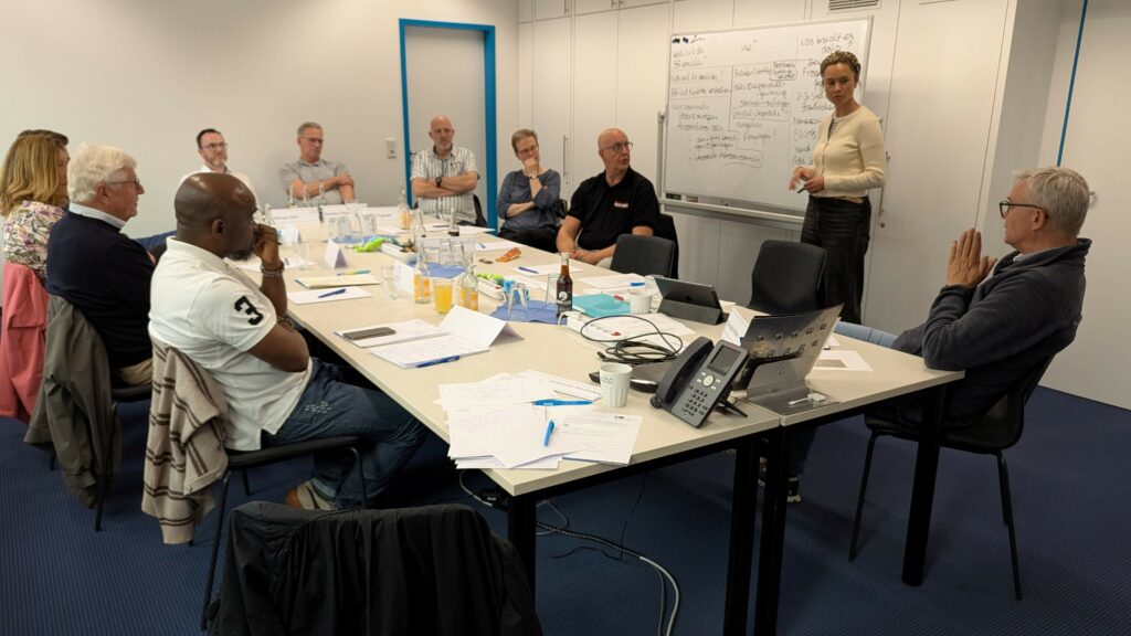 Personen sitzen in einem Besprechungsraum mit einen FlipChart
