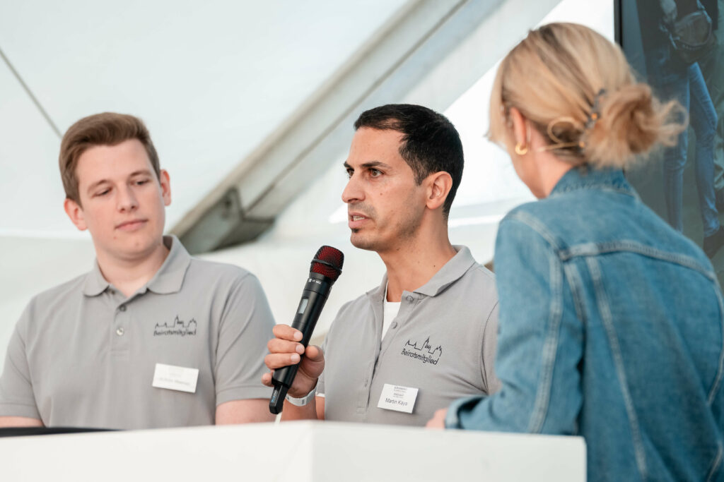 Person hat ein Mikrofon in der Hand und hält eine Rede
