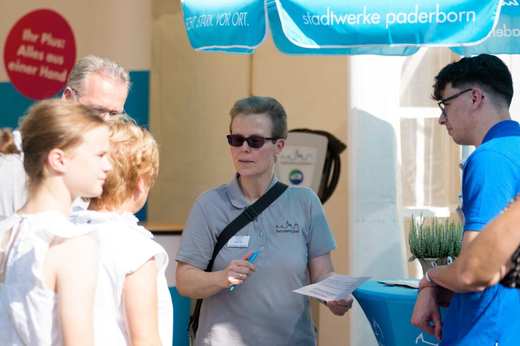 Eine Person mit Sonnenbrille hält einen Zettel und Stift in der Hand