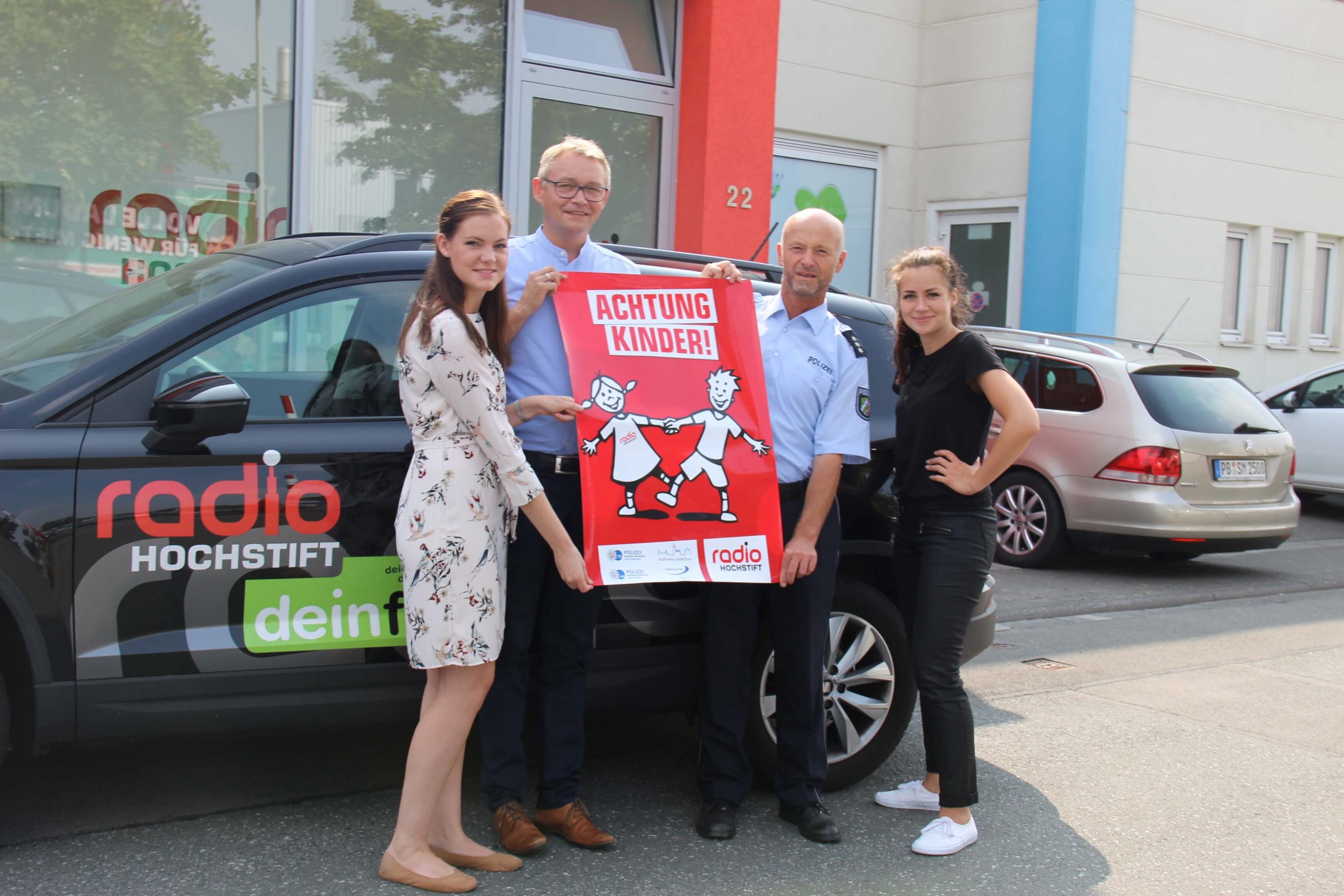 Achtung Kinder Aktion mit 4 Personen vor einem Auto die ein Kampagnen Plakat halten